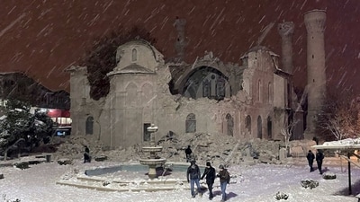 People walk next to a mosque destroyed by a massive earthquake in Malatya, Turkey on Monday, (AP)