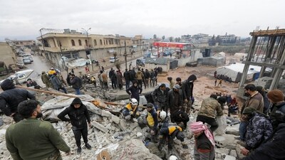 People gather as rescuers search for survivors under the rubble, following an earthquake, in rebel-held town of Jandaris, Syria. (REUTERS)