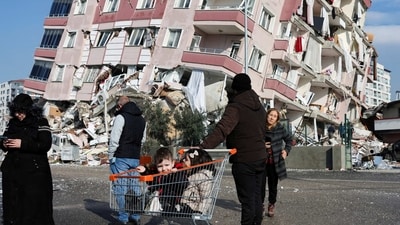 Turkey 5th earthquake: Children sit in a shopping cart near a collapsed building following an earthquake in Hatay, Turkey. (Reuters)