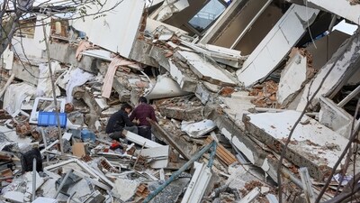 People stand on rubble as the search for survivors continues following an earthquake in Hatay Province in Turkey. (Reuters)
