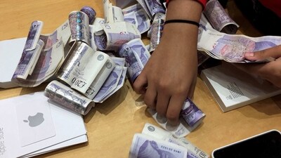 A shop assistant counts piles of British Pound Sterling banknotes at an Apple store in London, Britain. (REUTERS file)