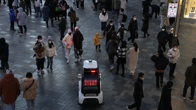 A police robot vehicle patrols near the crowd that has returned to a mall following the easing of pandemic restrictions in Beijing, Sunday. (AP file) A police robot vehicle patrols near the crowd that has returned to a mall following the easing of pandemic restrictions in Beijing, Sunday. (AP file)
