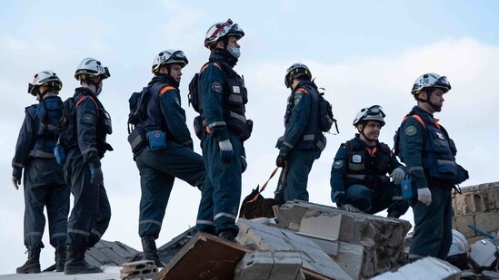 Rescue personnel search for survivors and victims under the rubble of a collapsed building in the town of Jableh in Syria's northwestern province of Latakia following an earthquake. (AFP)