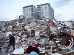 People walk amid rubble following an earthquake in Hatay, Turkey.