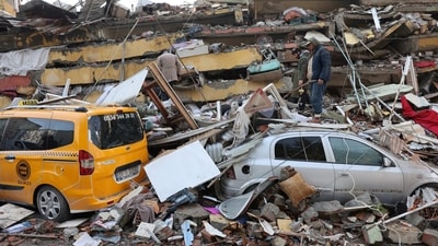 People inspect the damage as rescuers search for survivors in the aftermath of a deadly earthquake in Hatay, Turkey. (REUTERS)