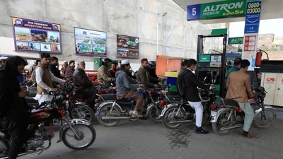 People wait for their turn to get fuel at a petrol station in Peshawar, (REUTERS)