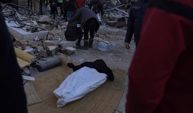 People stand around a dead body taken out from the rubble of a destroyed building in Antakya, southern Turkey, on Thursday, (AP) People stand around a dead body taken out from the rubble of a destroyed building in Antakya, southern Turkey, on Thursday, (AP)