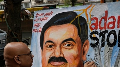 An artist gives final touches to a painting of Gautam Adani, depicting the ongoing crisis of the Adani group, in Mumbai, (AP)