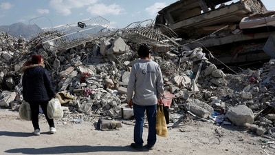 People walk by demolished buildings following the deadly earthquake in Iskenderun, Turkey, February 12, 2023. REUTERS/Benoit Tessier (REUTERS)