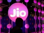 A man walks across the LED board showing the logo of Jio.