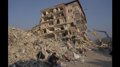 A man sits in the rubble of collapsed collapsed building in Antakya, Turkey. (AP File)