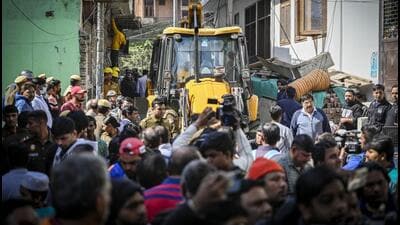 People gather around a backhoe loader demolishing a residential building in Mehrauli on Tuesday. (Raj k Raj/HT Photo) People gather around a backhoe loader demolishing a residential building in Mehrauli on Tuesday. (Raj k Raj/HT Photo)