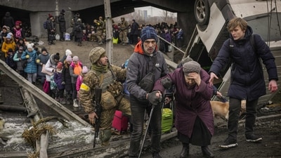 An elderly woman is assisted while crossing the Irpin River on an improvised path under a bridge that was destroyed by Ukrainian troops designed to slow any Russian military advance, while fleeing the town of Irpin, Ukraine, March 5, 2022. (AP Photo/Vadim Ghirda) (AP) An elderly woman is assisted while crossing the Irpin River on an improvised path under a bridge that was destroyed by Ukrainian troops designed to slow any Russian military advance, while fleeing the town of Irpin, Ukraine, March 5, 2022. (AP Photo/Vadim Ghirda) (AP)
