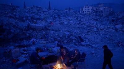 Local residents waiting for news of their relatives, sit by a bonfire near the rubble of collapsed buildings in Hatay, Turkey. (AFP) Local residents waiting for news of their relatives, sit by a bonfire near the rubble of collapsed buildings in Hatay, Turkey. (AFP)