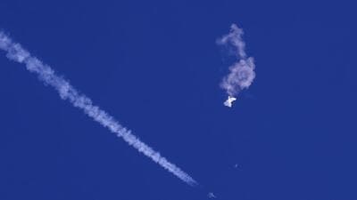 The remnants of a Chinese spy balloon drift above the Atlantic Ocean, just off the coast of South Carolina, with a fighter jet and its contrail seen below it, on February 4. (AP)