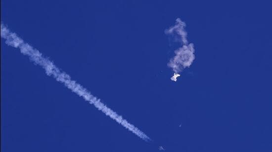The remnants of a Chinese spy balloon drift above the Atlantic Ocean, just off the coast of South Carolina, with a fighter jet and its contrail seen below it, on February 4. (AP)