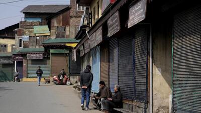 People sit outside closed shops in Srinagar on Wednesday. (AP) People sit outside closed shops in Srinagar on Wednesday. (AP)