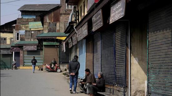 People sit outside closed shops in Srinagar on Wednesday. (AP)