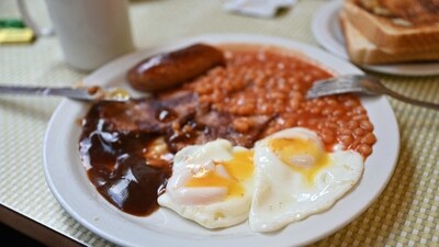A full English breakfast with eggs, baked beans, bacon, sausage and gravy sauce is served on a table. (AFP)
