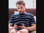 The image shows Anupam Mittal looking at his smartphone.