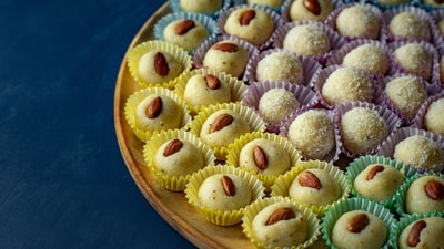 Laddu: Laddu is a ball-shaped sweet made from various ingredients, such as gram flour, semolina, or coconut. It is believed to have originated in the Middle East and was introduced to India by the Mughals.&nbsp; (Unsplash)