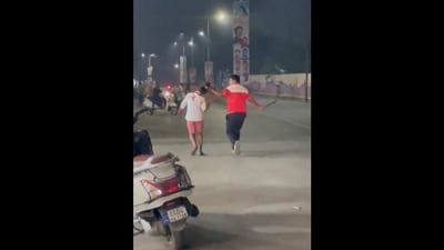 In a video doing rounds on social media, a man can be seen pulling a woman by her hair as he drags her mercilessly on a busy road, with a knife-like weapon swinging from his other hand. (Videograb) In a video doing rounds on social media, a man can be seen pulling a woman by her hair as he drags her mercilessly on a busy road, with a knife-like weapon swinging from his other hand. (Videograb)