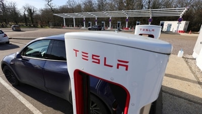 A driver recharges the battery of his Tesla car. (REUTERS)