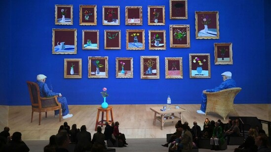 Visitors seen at the exhibit with Hockney's ‘Looking at the flowers’ in the background, in London, on February 22. The exhibit is divided into six themed chapters delving into his creative processes and accompanied by a musical score by American composer Nico Muhly.&nbsp;(Daniel Leal / AFP)