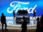 People walk by a Ford Escape SUV displayed during the media day for the Shanghai auto show in Shanghai.