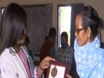 Polling officer presenting memento to voter who turned up in early hours for voting.