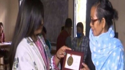 Polling officer presenting memento to voter who turned up in early hours for voting. (ANI)