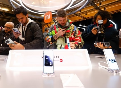 Visitors take pictures of Xiaomi 13 mobile phone models at the Xiaomi booth before the Mobile World Congress 2023 in Barcelona, Spain, on Sunday, (AP)