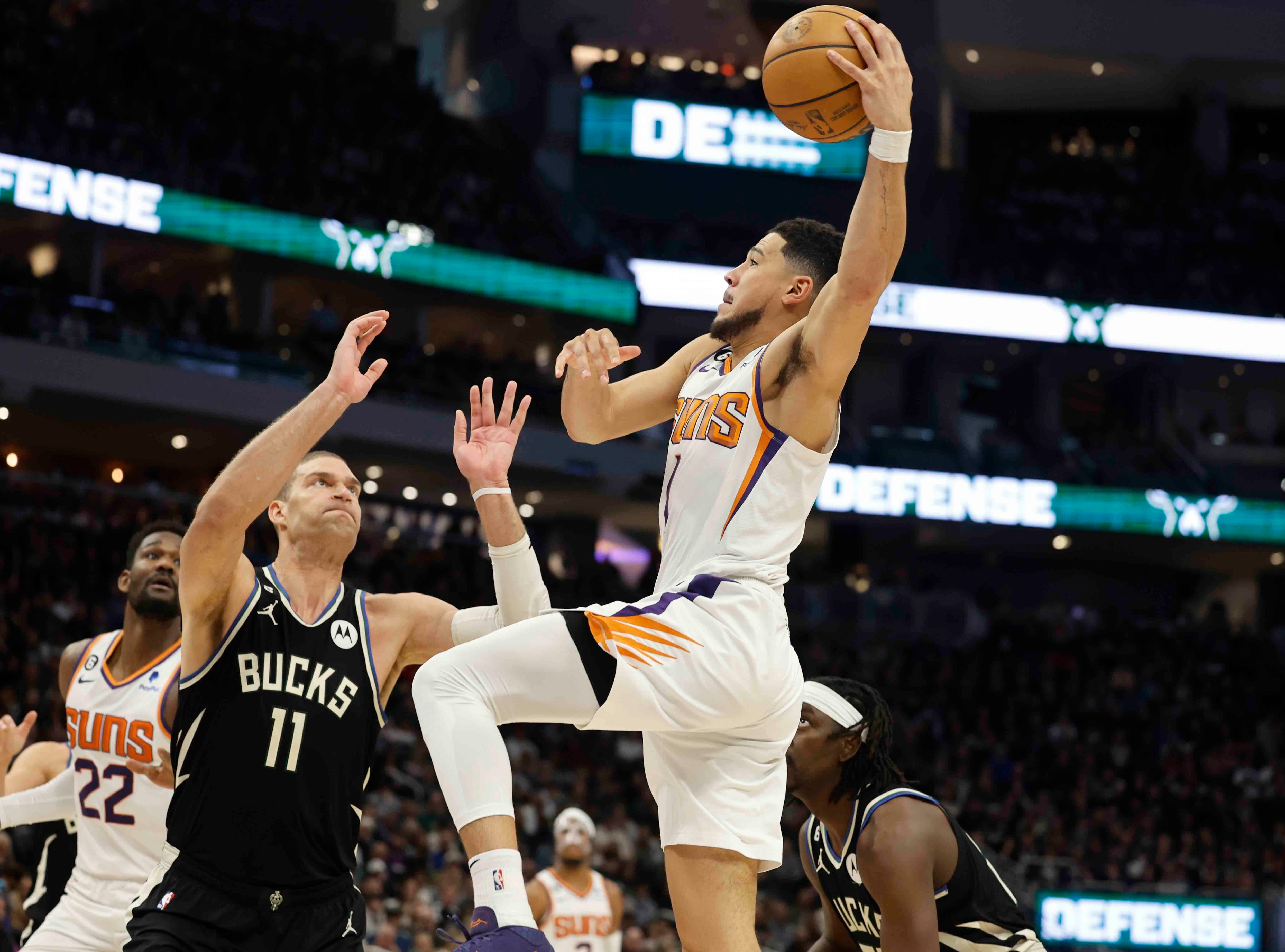 Phoenix Suns guard Devin Booker (1) drives against Milwaukee Bucks center Brook Lopez (11) during the second half of an NBA basketball game Sunday, (AP) Phoenix Suns guard Devin Booker (1) drives against Milwaukee Bucks center Brook Lopez (11) during the second half of an NBA basketball game Sunday, (AP)