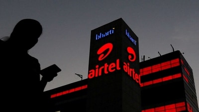 A girl checks her mobile phone as she walks past the Bharti Airtel office building in Gurugram, on the outskirts of New Delhi. (REUTERS)
