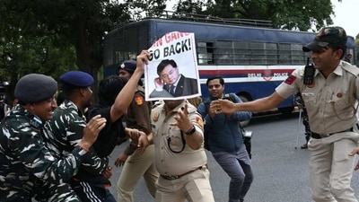 Police try to hold a protestor carrying anti-China poster with “Qin Gang, Go Back” written on it.&nbsp; (Vipin Kumar/ Hindustan Times)