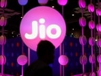A man walks across the LED board showing the logo of Jio