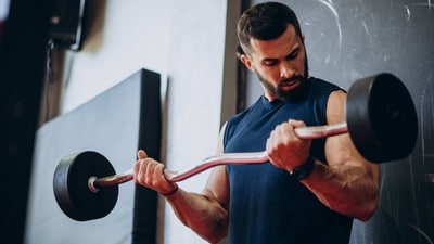 EZ-Bar Curl: This exercise is similar to the barbell curl but uses an EZ-bar. Start by standing with your feet shoulder-width apart and holding an EZ-bar in front of your thighs with an overhand grip. Keeping your elbows close to your body, curl the EZ-bar up until your forearms touch your biceps. Slowly lower the EZ-bar back to the starting position. (freepik)
