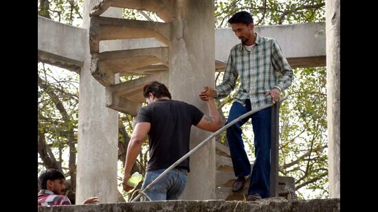 The man (in shirt), who had climbed atop a water tank at the mini-secretariat, being brought down by a friend in Ludhiana on Thursday. (Gurpreet Singh/HT photo)