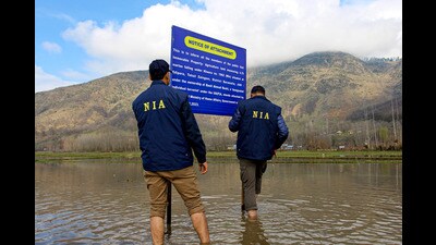 Members of an NIA team put up a notice board on the attached land belonging to Pakistan-based terrorist Basit Ahmad Reshi in Baramulla on Friday. (PTI) Members of an NIA team put up a notice board on the attached land belonging to Pakistan-based terrorist Basit Ahmad Reshi in Baramulla on Friday. (PTI)