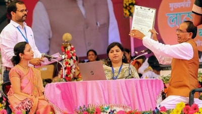 Madhya Pradesh Chief Minister Shivraj Singh Chouhan helps a beneficiary to fill her form during the launch of Mukhyamantri Ladli Behna Yojana. (PTI)