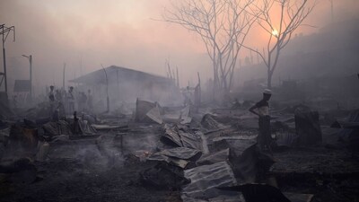 Rohingya refugees seen around fuming debris after a major fire at the Balukhali camp at Ukhiya in Cox's Bazar district, on March 5. The fire raced through a crammed camp of Rohingya refugees, leaving thousands homeless, a fire official and the United Nations told AP. (Mahmud Hossain Opu / AP)