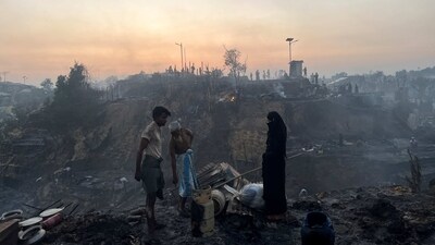 A Rohingya refugee family stands near their shelter that was destroyed by the fire. "My shelter was gutted. My shop was also burnt," said Mamun Johar, a 30-year-old Rohingya man. "The fire took everything from me, everything."&nbsp; (Ro Yassin Abdumonab / REUTERS)