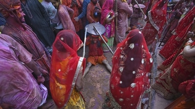 Men wear turbans and hold shields above their heads to protect themselves from women who are hitting them in the mock battle. (AP) Men wear turbans and hold shields above their heads to protect themselves from women who are hitting them in the mock battle. (AP)