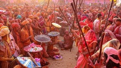 Hundreds of women in Nandgaon celebrated Holi by playfully hitting men with wooden sticks in response to their teasing as part of a ritual. (PTI) Hundreds of women in Nandgaon celebrated Holi by playfully hitting men with wooden sticks in response to their teasing as part of a ritual. (PTI)