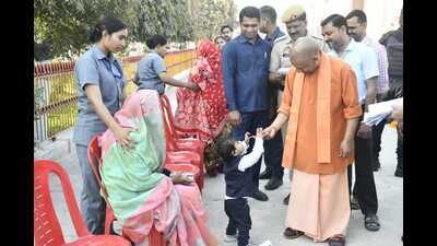Chief minister Yogi Adityanath giving sweets to a child at the Janta Darbar in Gorakhpur on Tuesday. (HT Photo)