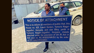 NIA officials pasting a board outside the attached property in Yamunanagar on Tuesday. (HT Photo)