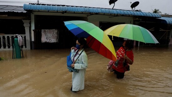People wade through a flooded residential area at Yong Peng, Johor, Malaysia. The country is facing unprecedented continuous torrential rain from the annual monsoon season that began in November 2022. An AFP report says the previous worst flooding in decades had been in 2014 when about 118,000 people fled their homes.&nbsp;(Hasnoor Hussain / Reuters)