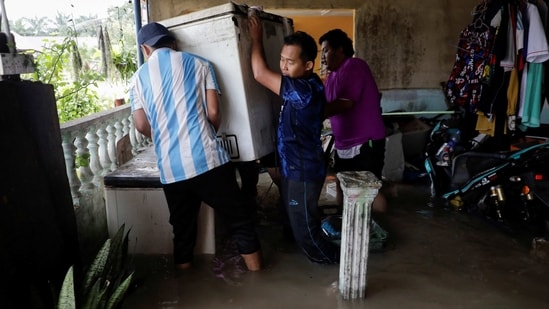 People move a refrigerator from a flooded house. Malaysia often experiences stormy weather towards the year end, with seasonal flooding regularly causing mass evacuations and deaths.(Hasnoor Hussain / Reuters)