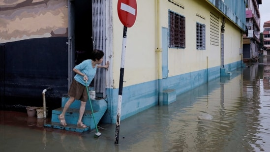 A woman checks the surrounding of her residence, as floodwaters recede. Several other states including remote areas on Borneo island were also hit by torrential rain causing floods, reported AP. &nbsp;(Hasnoor Hussain / Reuters)