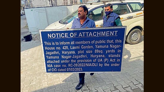 NIA officials pasting a board outside the attached property in Yamunanagar on Tuesday. (HT Photo)